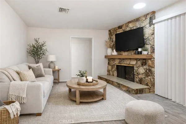 a view of an empty room with wooden floor and a fireplace