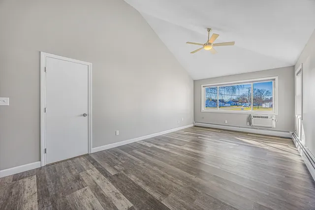 a view of an empty room with a window and wooden floor