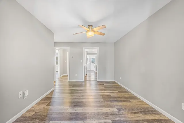 a view of an empty room with window and wooden floor