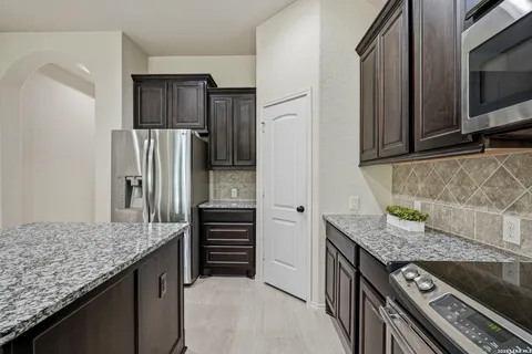 a kitchen with granite countertop a refrigerator and stove