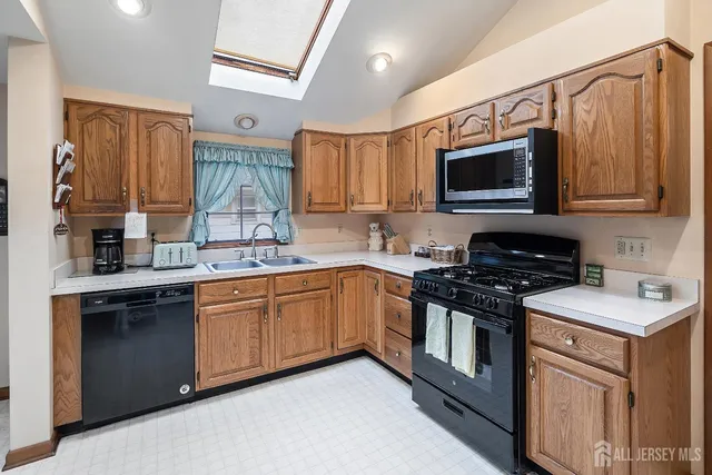 a kitchen with stainless steel appliances granite countertop a stove top oven a sink dishwasher and white cabinets with wooden floor