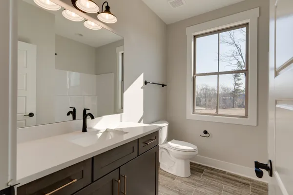 a bathroom with a toilet a sink a mirror and a window