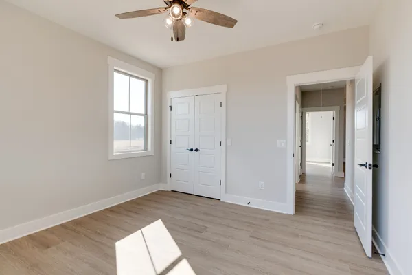 a view of empty room with wooden floor and fan