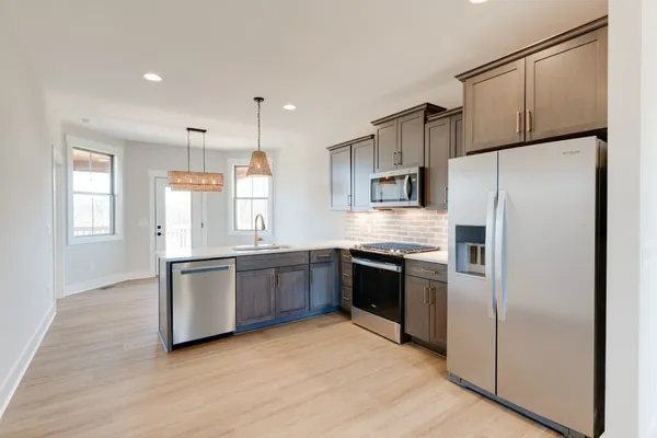 a kitchen with granite countertop stainless steel appliances a refrigerator cabinets and wooden floor