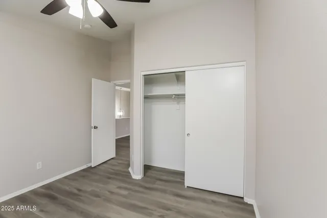 a view of an empty room with wooden floor closet and a window