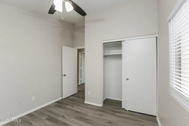 an empty room with wooden floor chandelier fan and windows