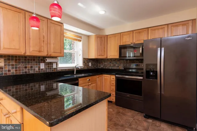 a kitchen with stainless steel appliances granite countertop a sink a stove and a refrigerator