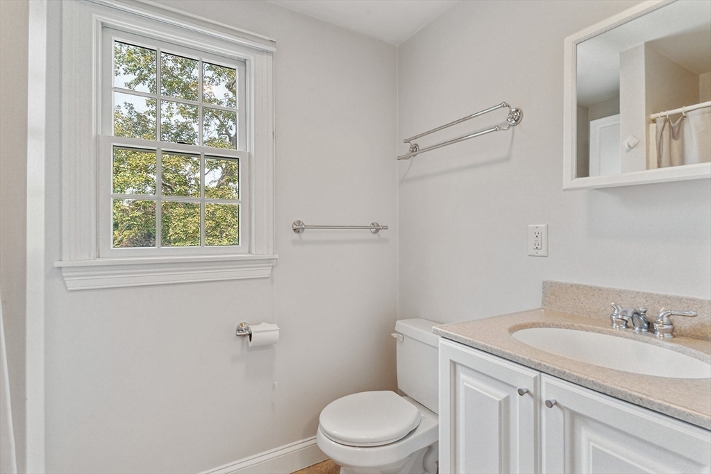 166 Forest Street Winchester, MA 01890 - Photo 26 of 37 a bathroom with a granite countertop toilet a sink a mirror and a window