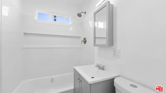 a kitchen with a faucet and white cabinets with wooden floor