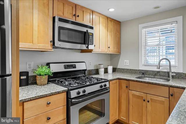 a kitchen with granite countertop a stove top oven microwave and cabinets