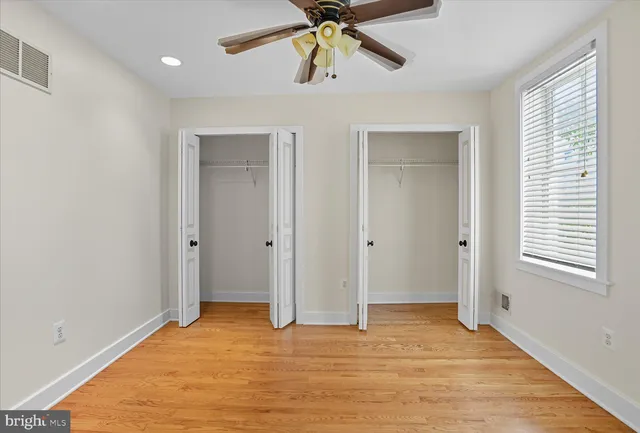 a view of an empty room with window and wooden floor