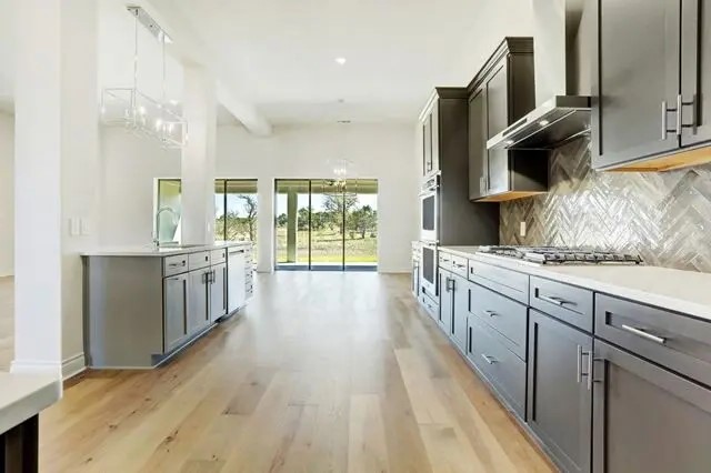 104 Lazy Oak Place Spicewood, TX 78669 - Photo 26 of 40 a large kitchen with stainless steel appliances a large counter top a stove and a sink