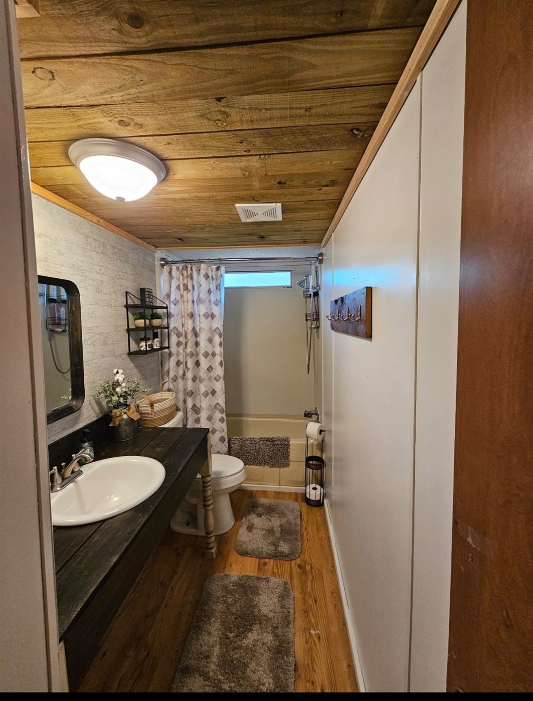 390 Wharf Road Savannah, TN 38372 - Photo 11 of 17 Bathroom featuring a dark wood-finish vanity with a white vessel sink, wood-finish flooring, a neutral-toned bathtub, a flush-mount ceiling light, and a wood-plank ceiling