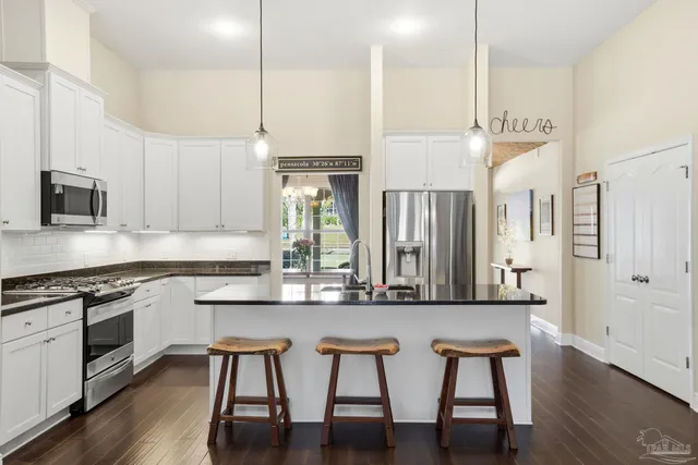 a living room with furniture kitchen view and a wooden floor