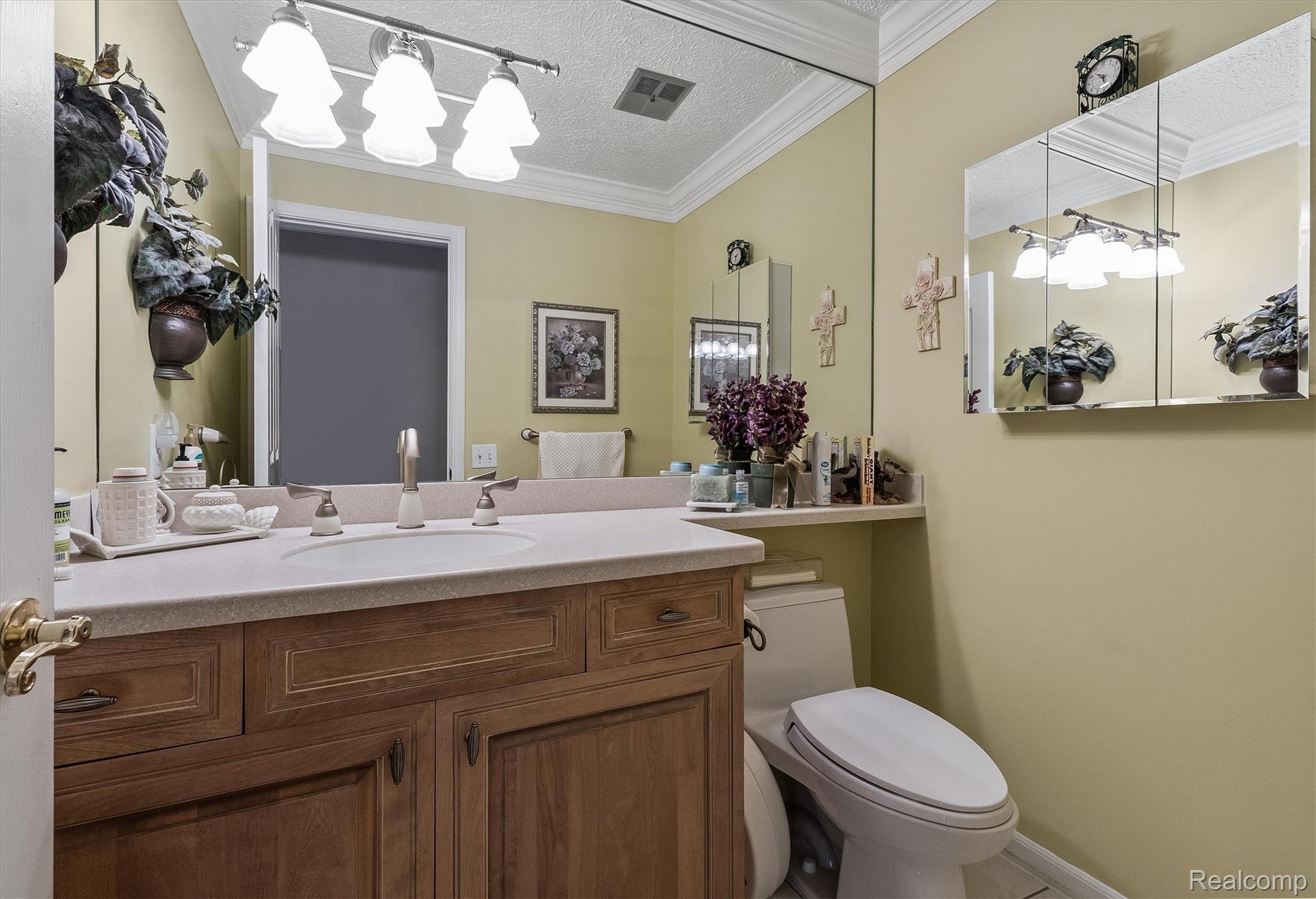 1662 Sumac Drive Rochester, MI 48309 - Photo 18 of 38 Bathroom featuring a wood-finish vanity with an integrated sink and light-toned countertop, a full-wall mirror, and a three-panel mirrored medicine cabinet