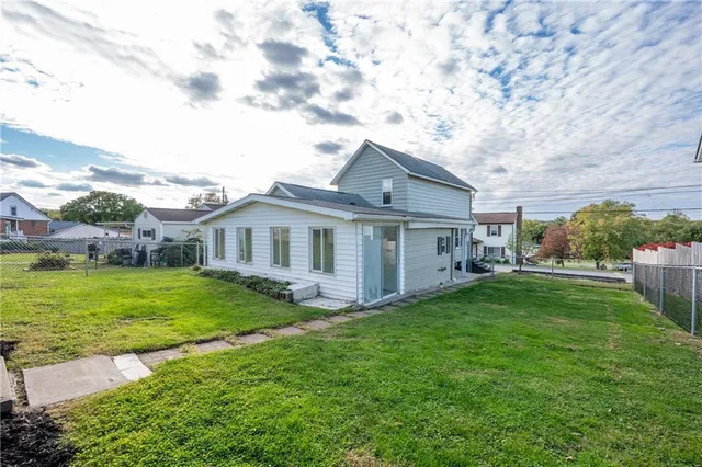 a backyard of a house with plants and large tree