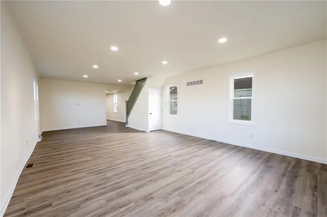 an empty room with wooden floor and windows