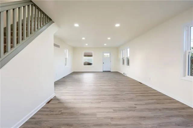 a view of an empty room with wooden floor and stairs
