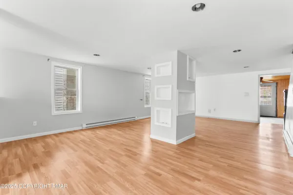 a view of empty room with wooden floor and window