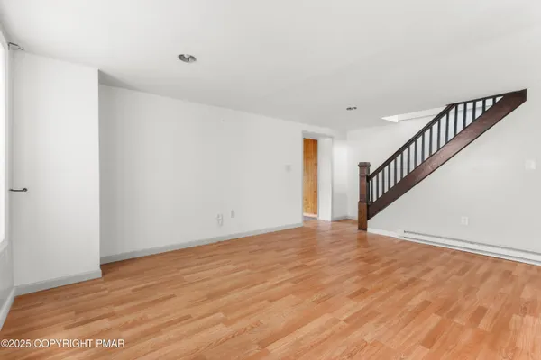 a view of an empty room with wooden floor and stairs