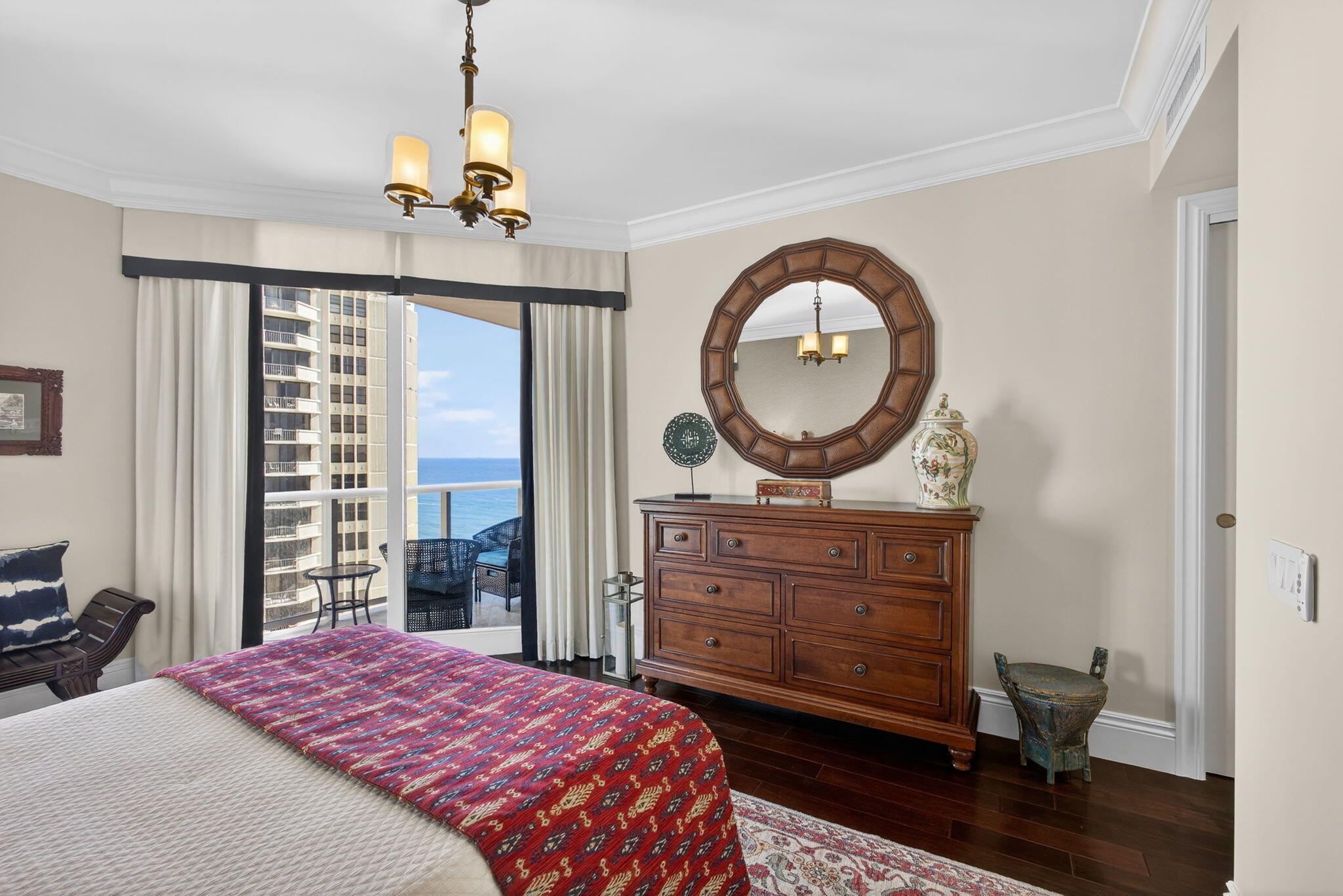 2700 North Ocean Drive, Unit 1401A Riviera Beach, FL 33404 - Photo 60 of 116 a bedroom with a bed a mirror on dresser and a chandelier