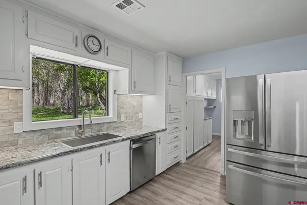 a kitchen with stainless steel appliances granite countertop a refrigerator and a sink