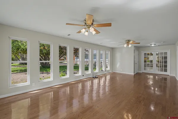 a view of an empty room with a window and wooden floor