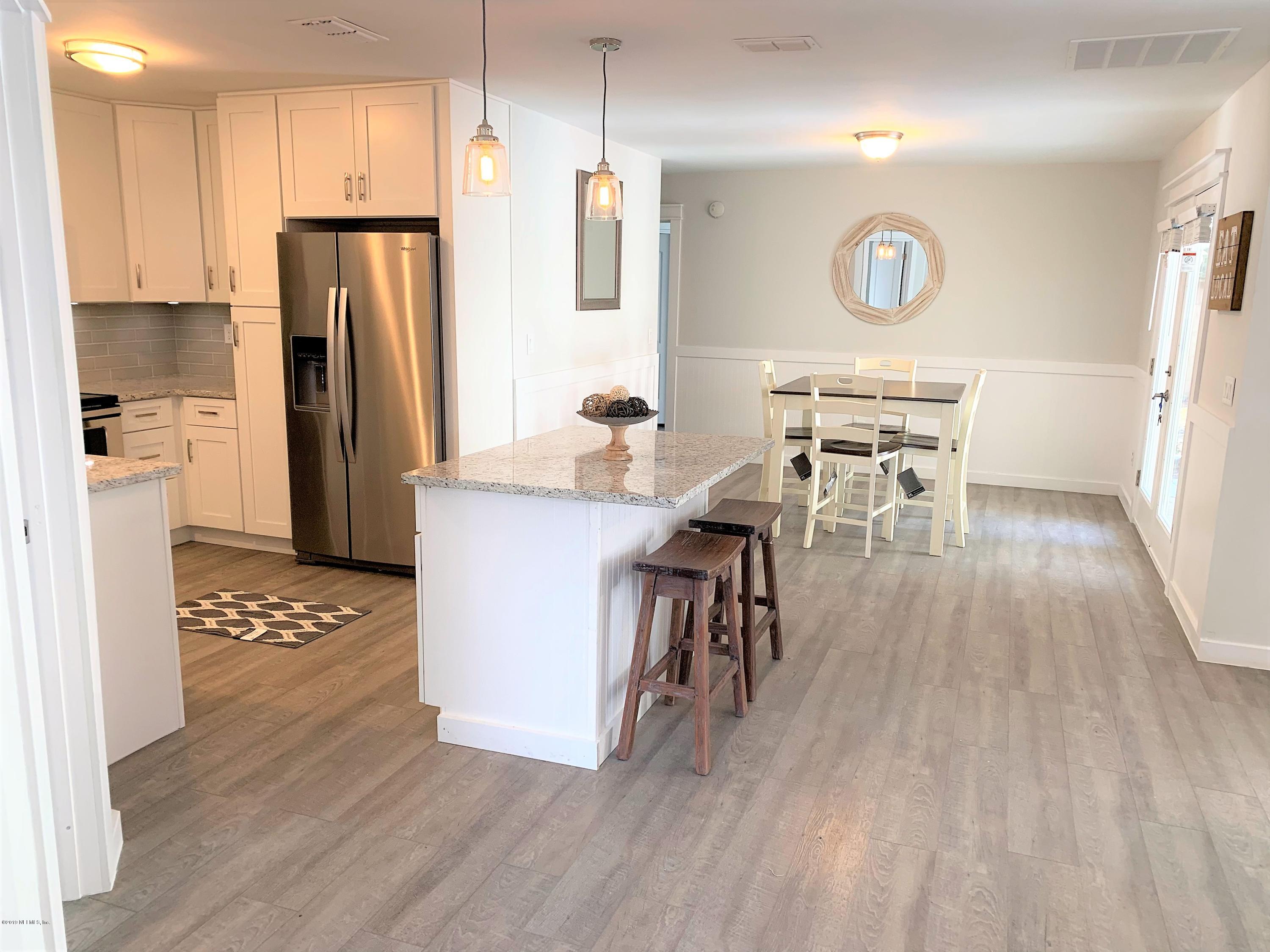 3300 Turtle Creek Road St. Augustine, FL 32086 - Photo 7 of 35 a kitchen with stainless steel appliances a refrigerator a stove a microwave oven a dining table and chairs with wooden floor