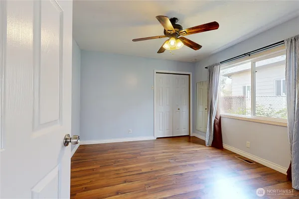 a view of an empty room with wooden floor and a window