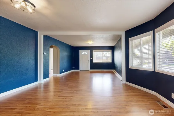 a view of an empty room with window and wooden floor