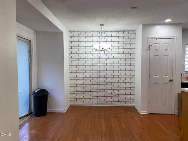 a view of an empty room with wooden floor and a bathroom