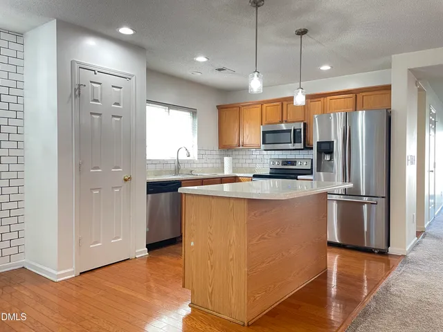 a kitchen with stainless steel appliances granite countertop a refrigerator a sink and a stove