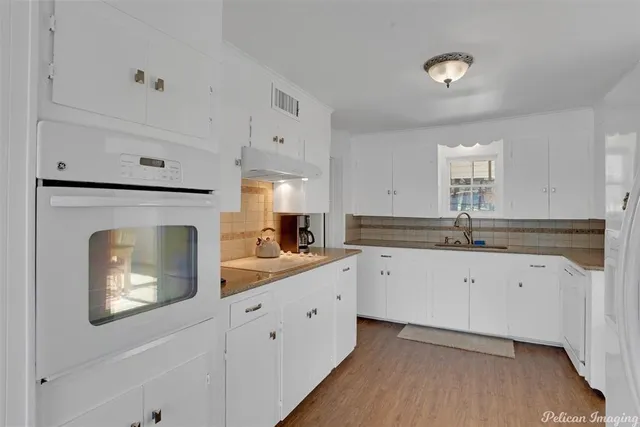 a kitchen with granite countertop white cabinets white stainless steel appliances with wooden floor