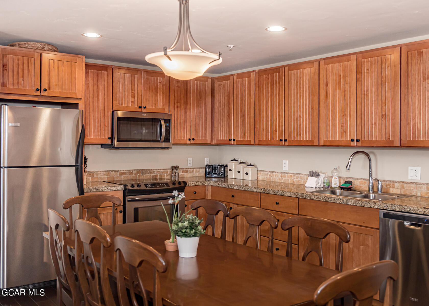 300 Base Camp Circle, Unit 208 Granby, CO 80446 - Photo 38 of 66 a kitchen with stainless steel appliances granite countertop a refrigerator a stove a sink a dining table and chairs with wooden floor