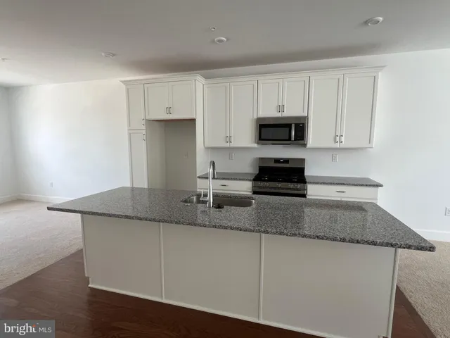 a kitchen with granite countertop white cabinets and a stove