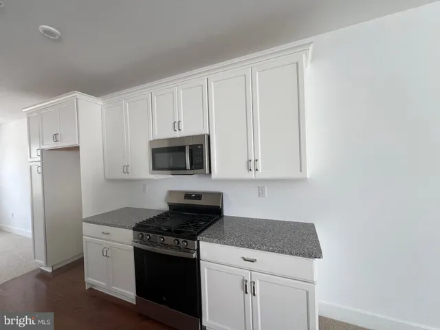 a kitchen with granite countertop white cabinets and stainless steel appliances
