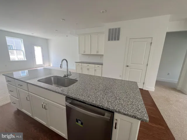 a kitchen with stainless steel appliances granite countertop a sink dishwasher and cabinets with wooden floor