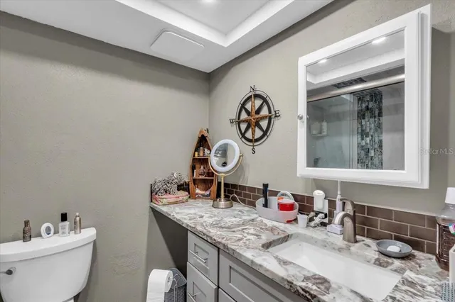 a bathroom with a granite countertop sink mirror vanity and toilet