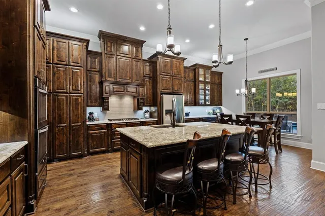 a kitchen with granite countertop a table chairs stove and refrigerator