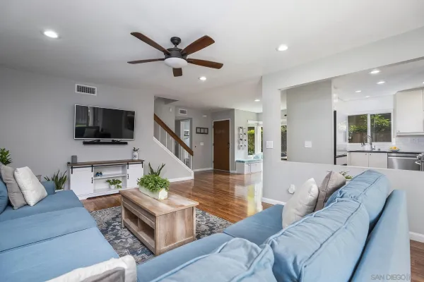 a living room with furniture and a flat screen tv with kitchen view