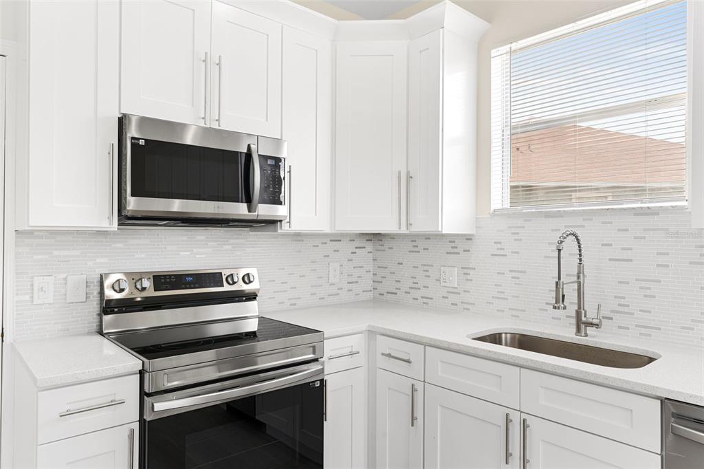 5424 Hammock View Lane Apollo Beach, FL 33572 - Photo 17 of 55 a kitchen with stainless steel appliances a stove microwave and sink