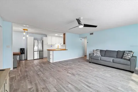 a kitchen with stainless steel appliances granite countertop a refrigerator a sink dishwasher a stove and white countertops with wooden floor