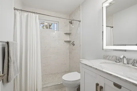 a bathroom with a granite countertop sink toilet and shower