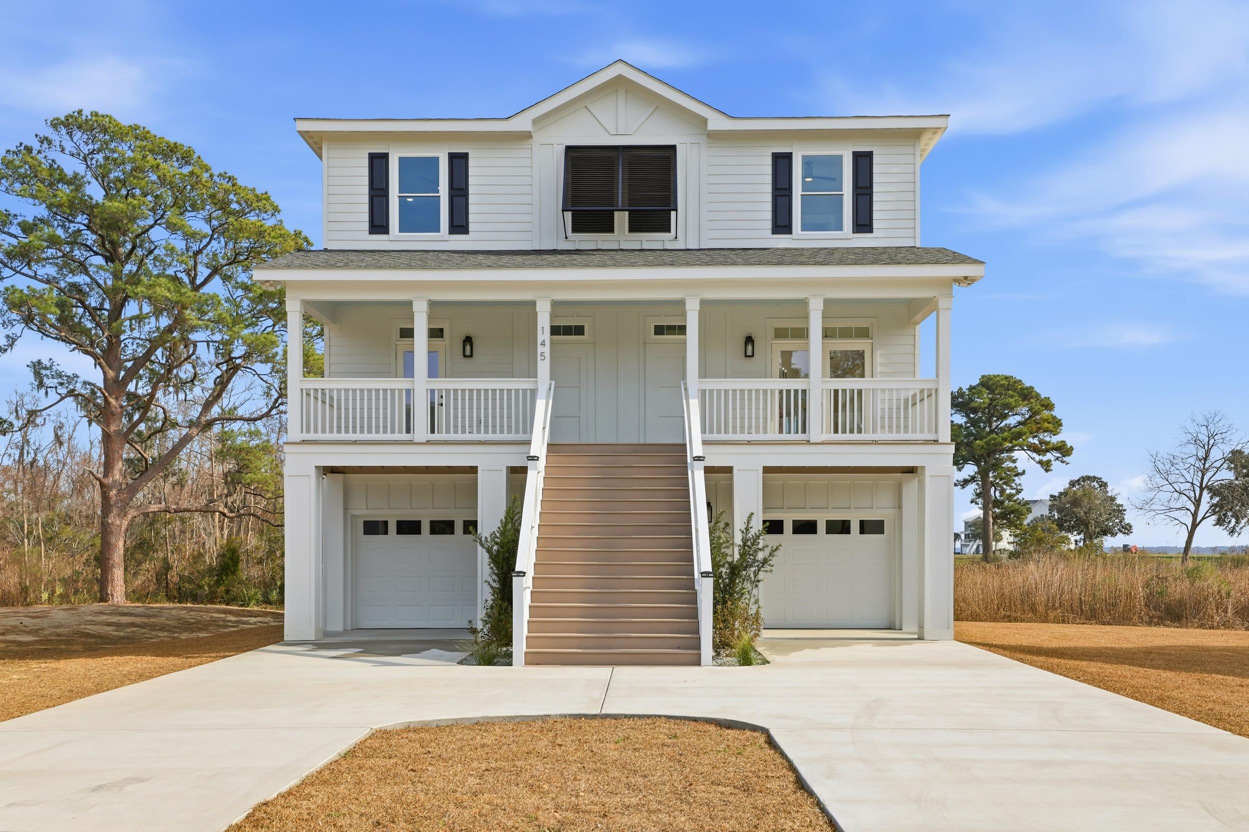 Coastal home featuring stairs, covered porch, and concrete driveway