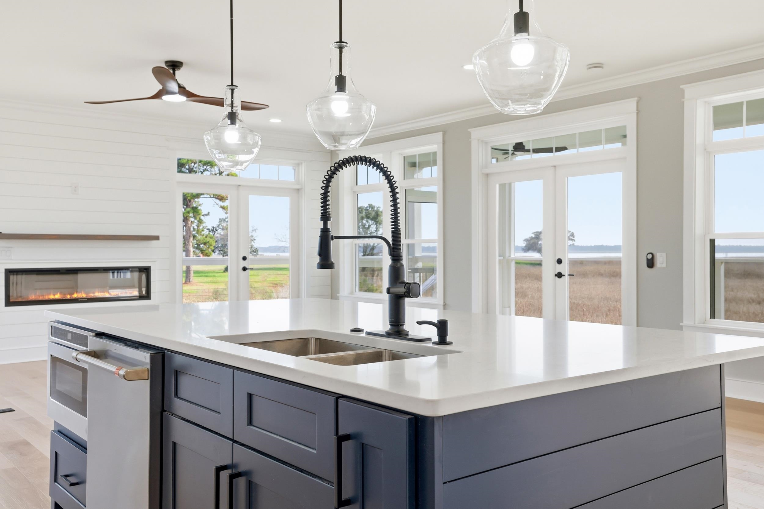 145 Oak Bay Drive Georgetown, SC 29440 - Photo 11 of 39 Kitchen with light wood-type flooring, french doors, a glass covered fireplace, crown molding, and pendant lighting