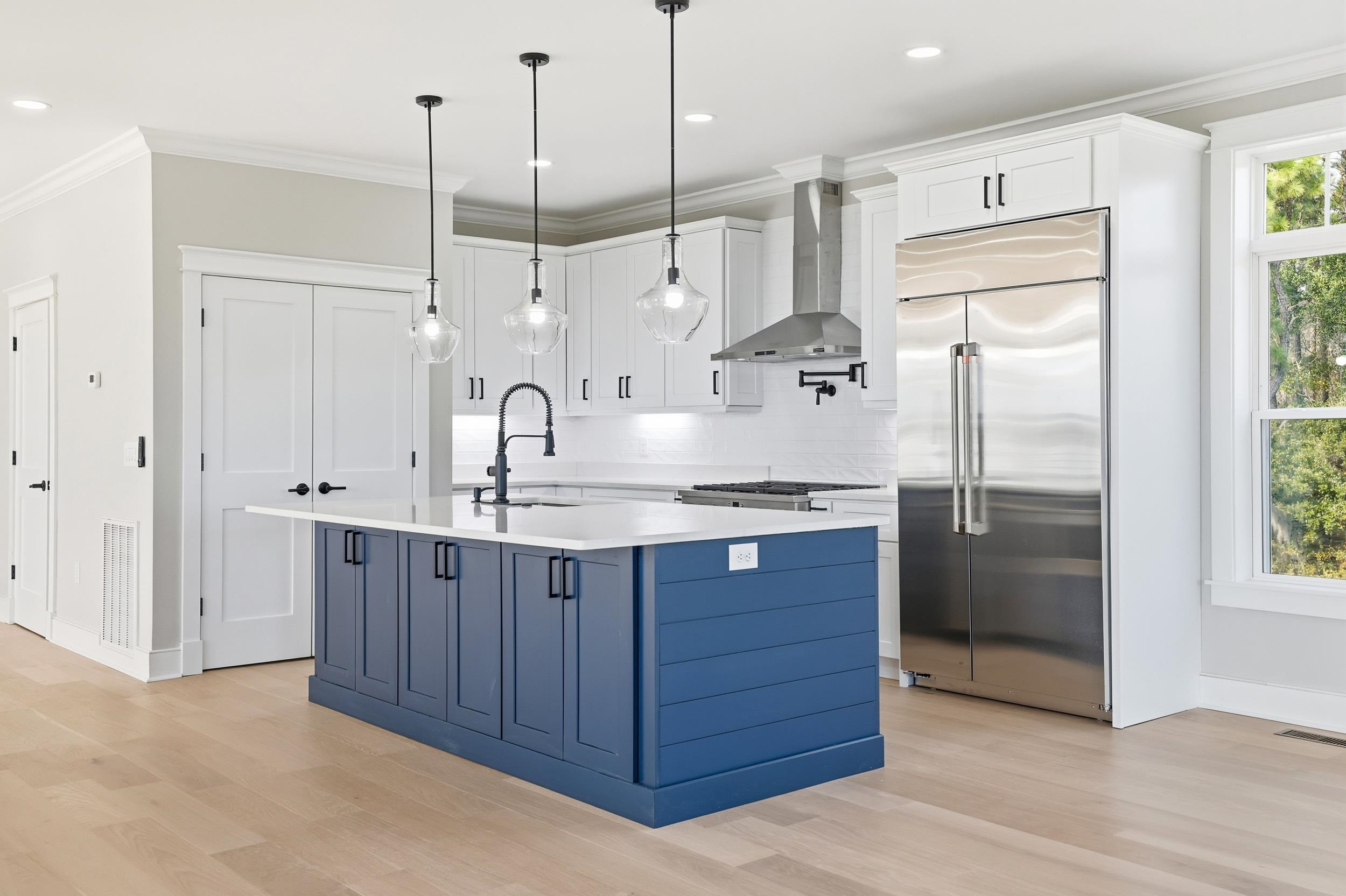 145 Oak Bay Drive Georgetown, SC 29440 - Photo 8 of 39 Kitchen featuring crown molding, white cabinetry, built in fridge, wall chimney exhaust hood, and an island with sink