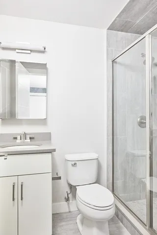 a bathroom with a toilet a sink a mirror and a shower