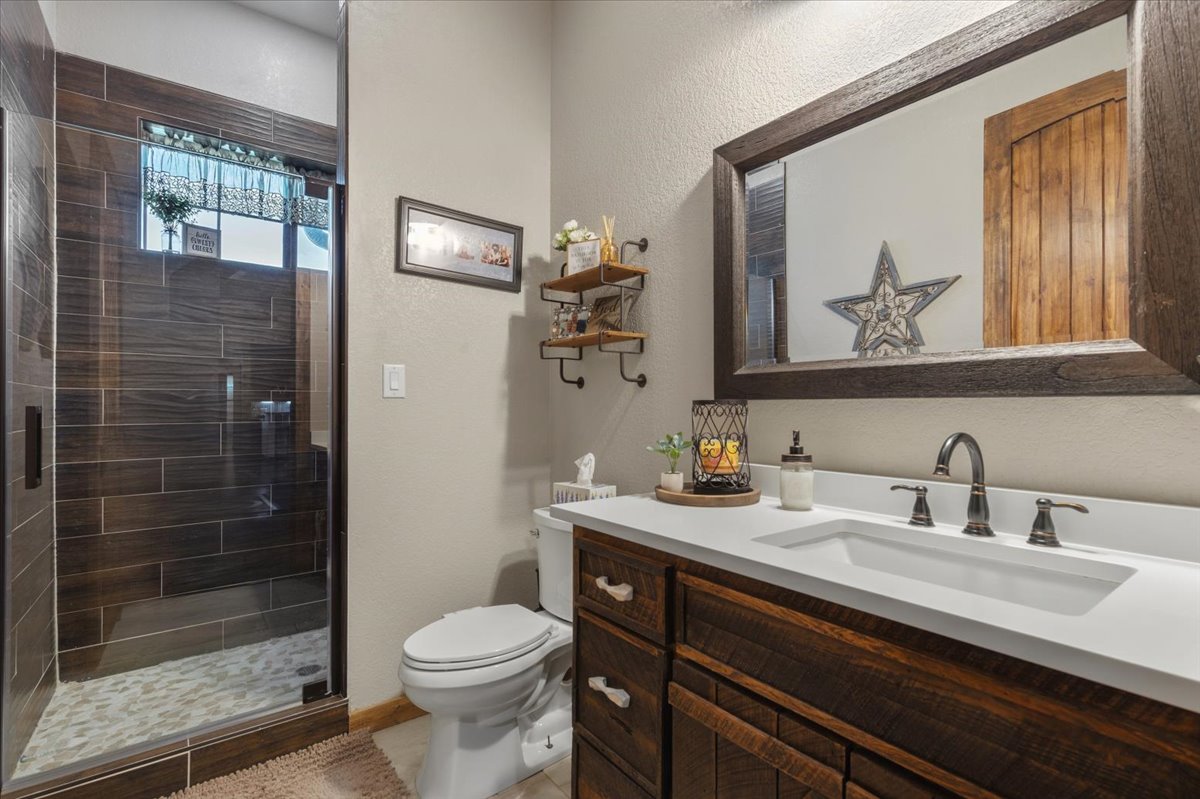 175 Wilson Road Elgin, TX 78621 - Photo 22 of 40 This full bath serving the guest room continues that high-end rustic theme. You’ve got a vanity with dark wood cabinets, modern fixtures, and a clean white countertop.
