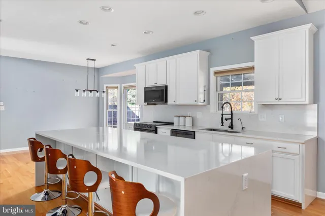 a kitchen with stainless steel appliances granite countertop a sink a stove and white cabinets