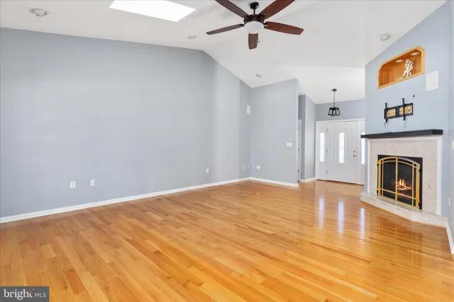 a view of an empty room with wooden floor and a fireplace